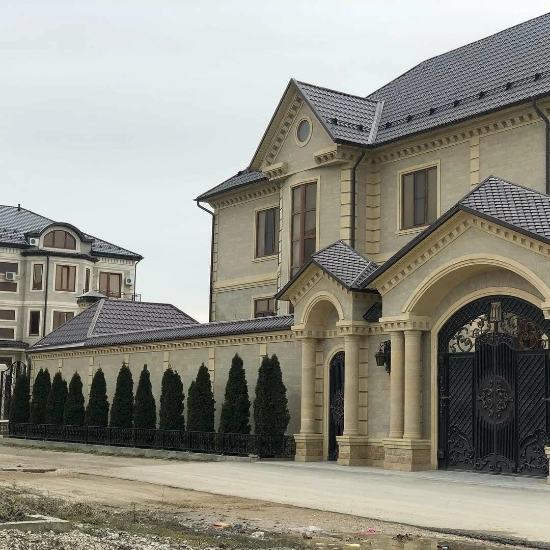 Выполненный фасад усадьбы из натурального камня с арочными воротами и колоннами