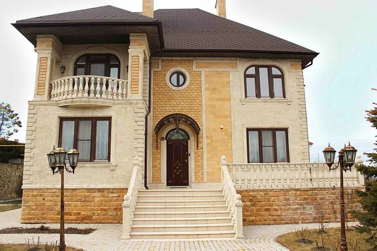 Светлый фасад частного дома с арочным порталом и наружными ступенями из камня